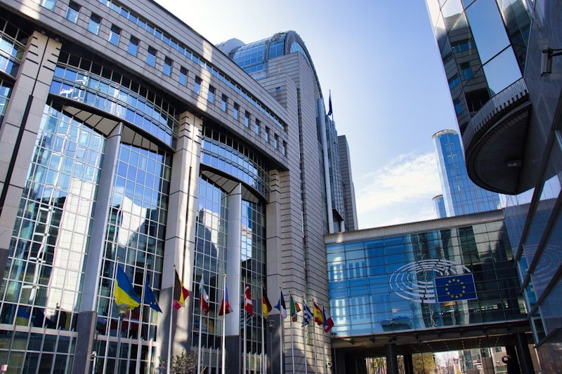 Prédio do Parlamento Europeu em Bruxelas com bandeiras da União Europeia — início da fiscalização da Lei de IA
