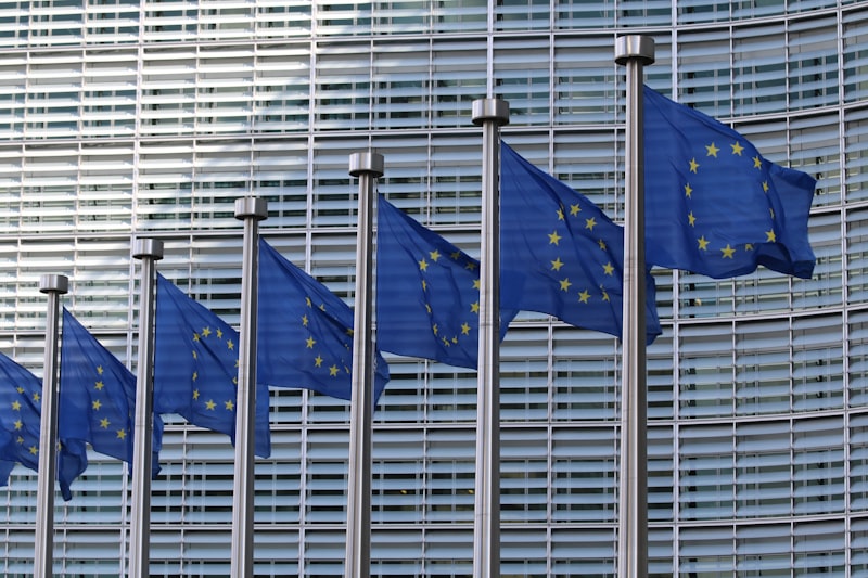 Bandeiras da União Europeia em frente a prédio institucional — regulação e transparência de IA